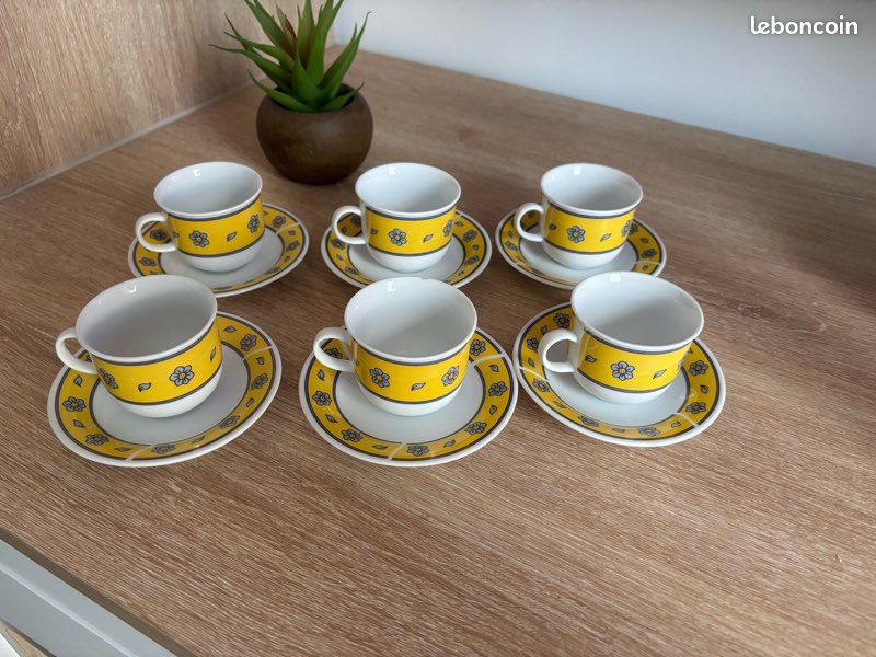 Deux tasses en céramique jaune sont soutenues par une main féminine
