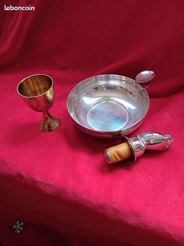 Fond de tiroir : un teste vin ouvide poché marque Daniel Hechter, métal argenté poinçon. Un coquetier en laiton avec un canard dessiné et un boucon avec une chouette. Le tarte vin fait 11 cm de diam (image 1)
