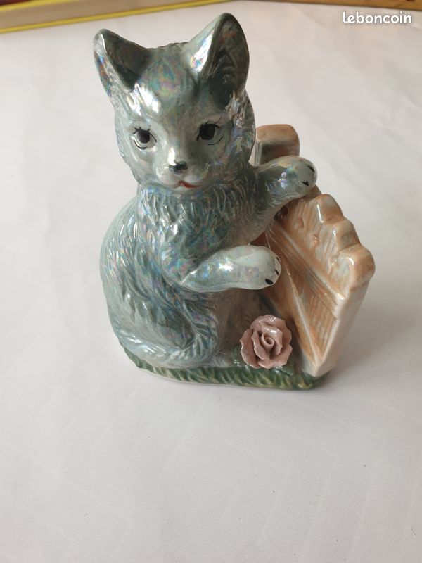 Petite figurine en céramique représentant un chat assis à côté d'une barrière (image 1)