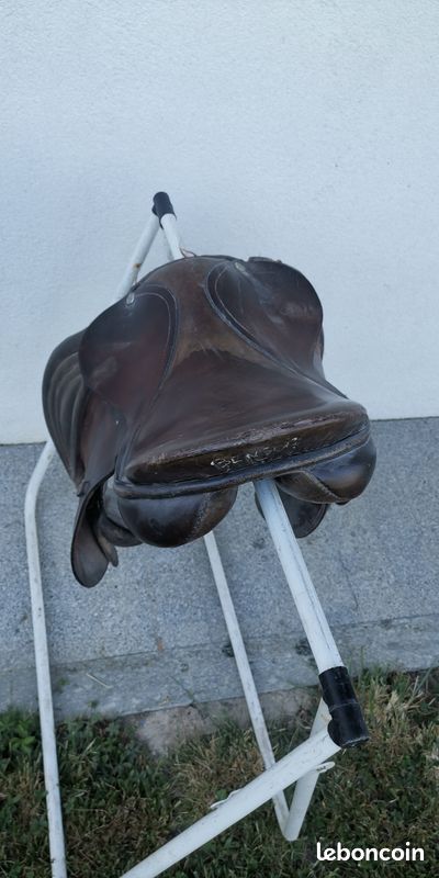 Ancienne Selle De Cheval En Cuir Usé Sur Une Clôture En Bois, éclairée