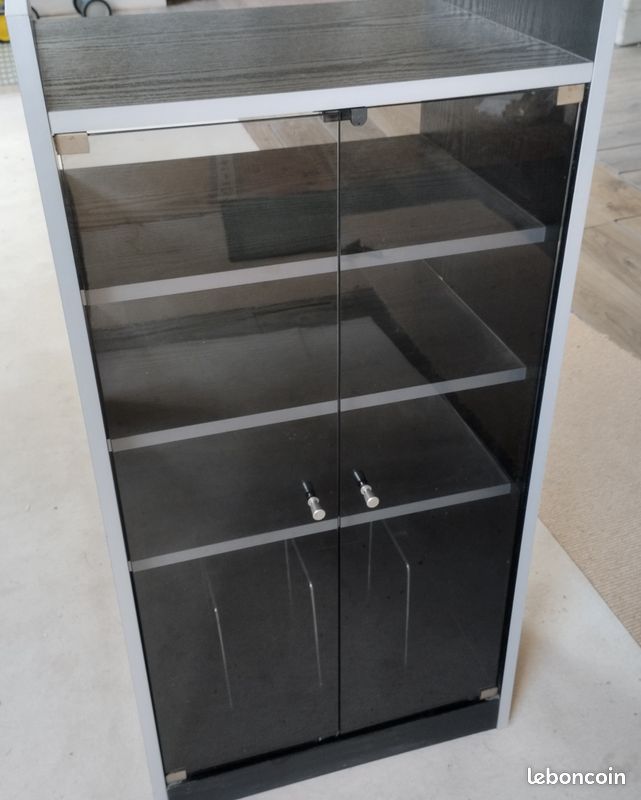 Meuble sur roulettes de rangement vertical doté d'une structure en bois mélaminé et de deux portes battantes en verre fumé et de plusieurs étagères (image 1)